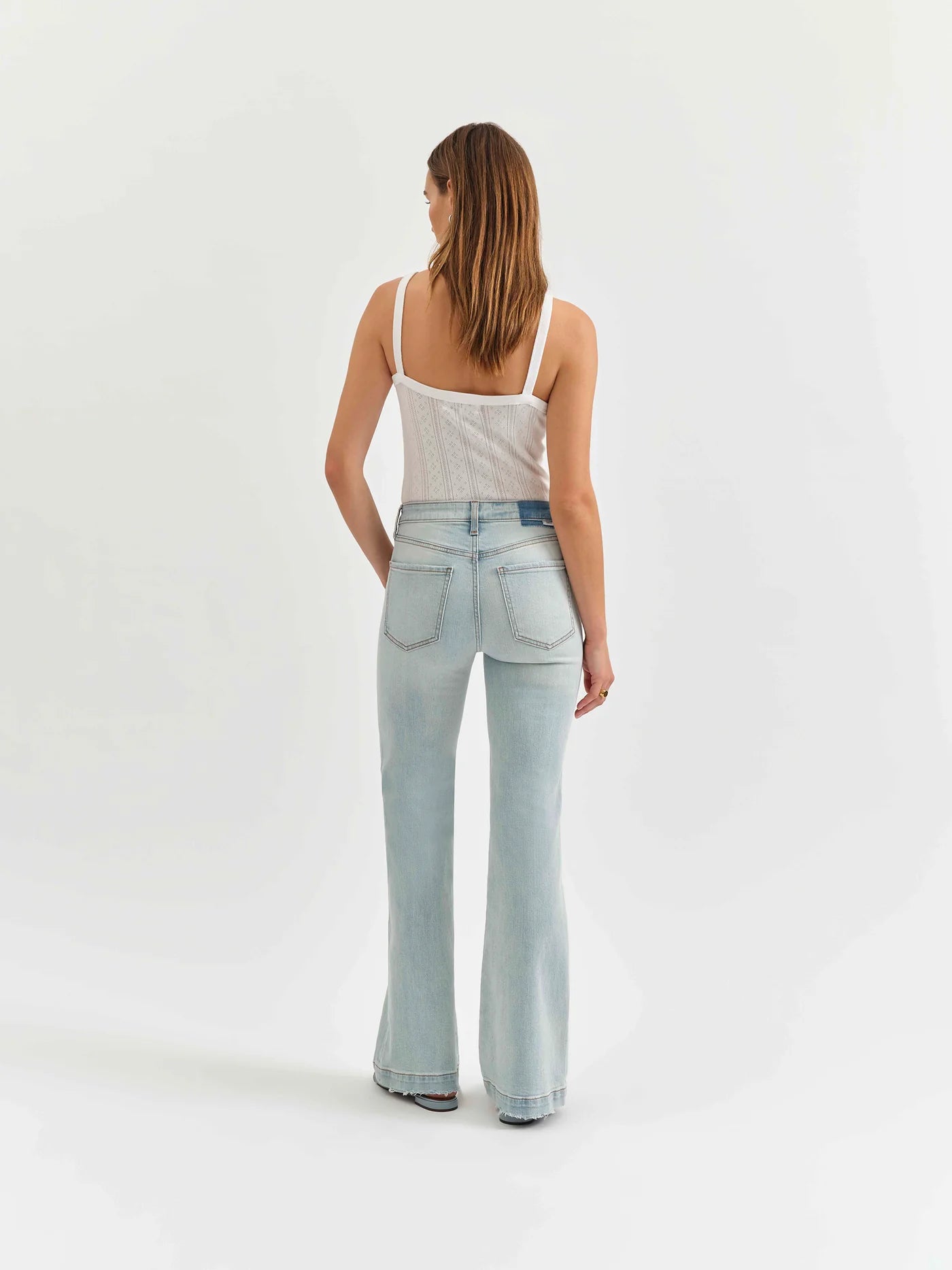 Back view of a model wearing the mid-rise flare jeans by Daze Denim in swoon vintage wash.