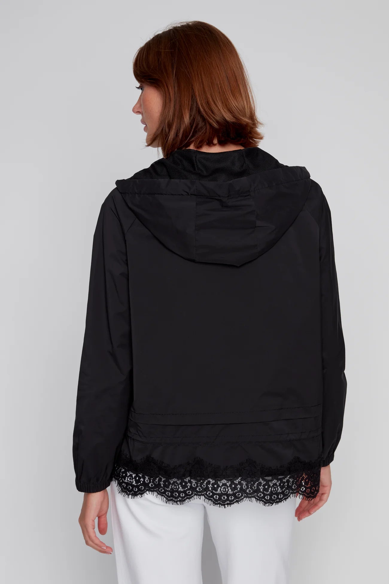 Back view of a model wearing a black CYC windbreaker with lace hem and hood.