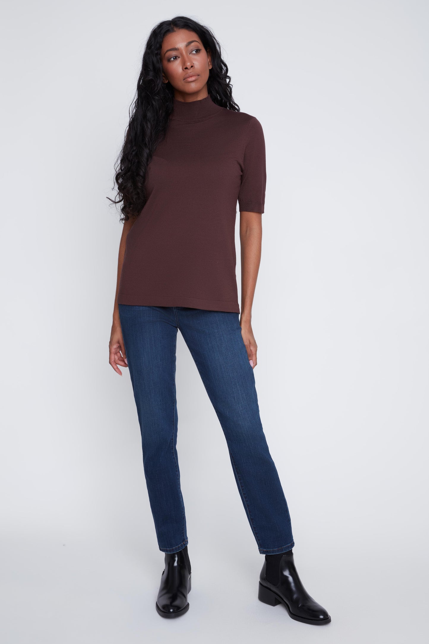 Model wearing an espresso coloured short sleeve mock neck top styled with dark denim jeans by CYC.