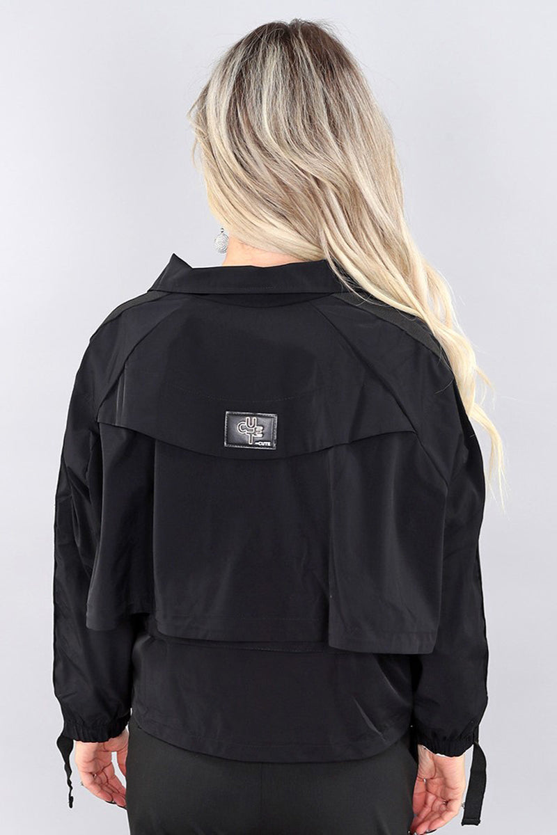 Back view of a model wearing black short polyester jacket by Michael Tyler.