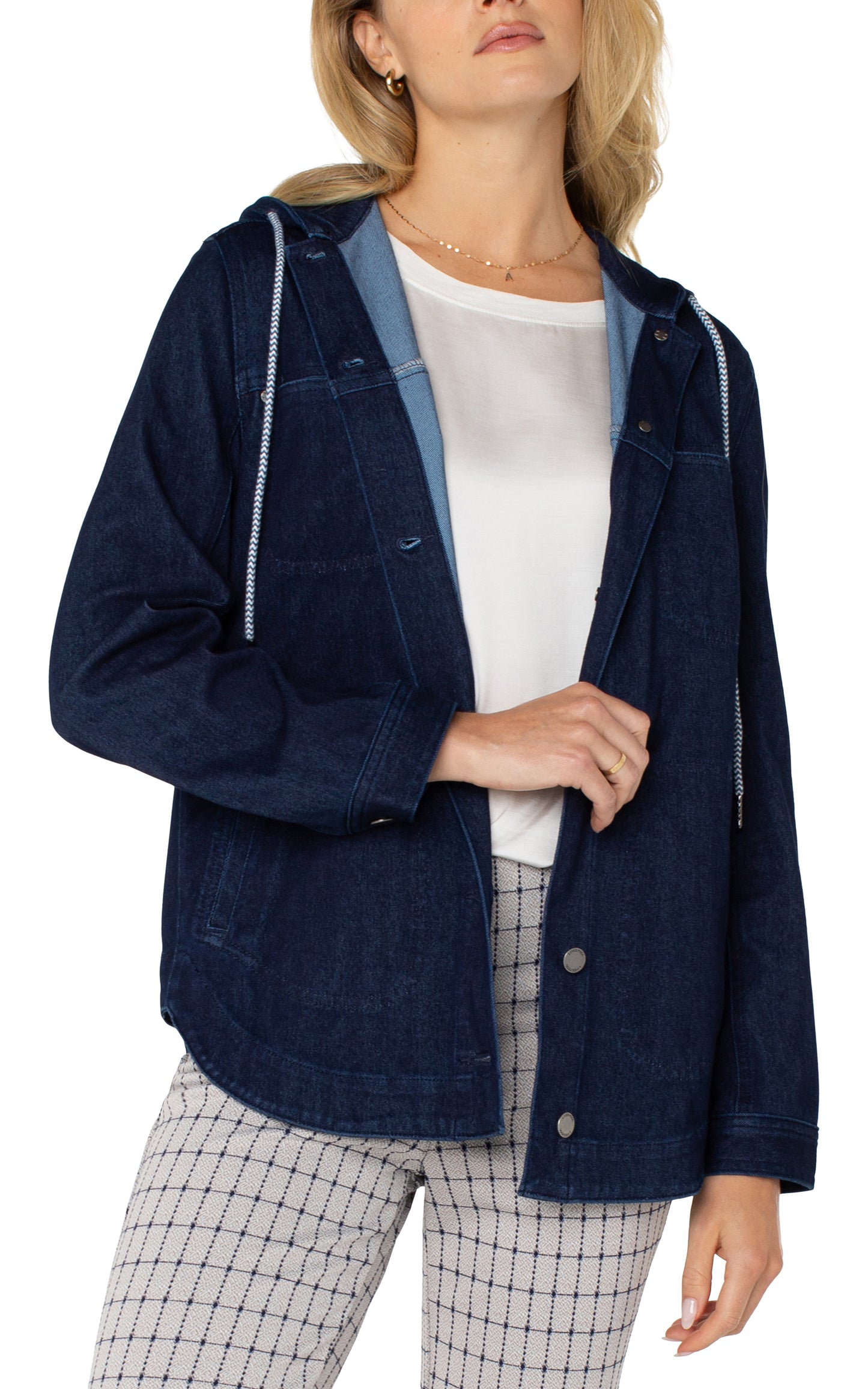 Model wearing the Liverpool hooded denim shirt jacket in Indigo Rinse, featuring a relaxed fit, button-up front, and drawstring hood. Styled with a white top and checkered pants.