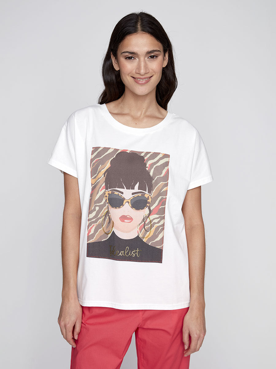 Model wearing white CYC graphic tee with sunglasses and “Idealist” text.