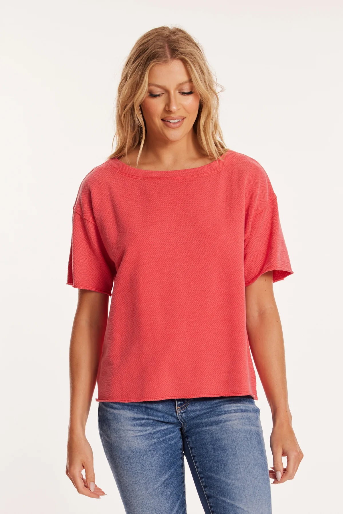 Model wears a fiery red boxy tee with a wide boat neckline and elbow-length sleeves. The relaxed, drop-shoulder fit and subtle textured fabric offer a modern yet casual silhouette.