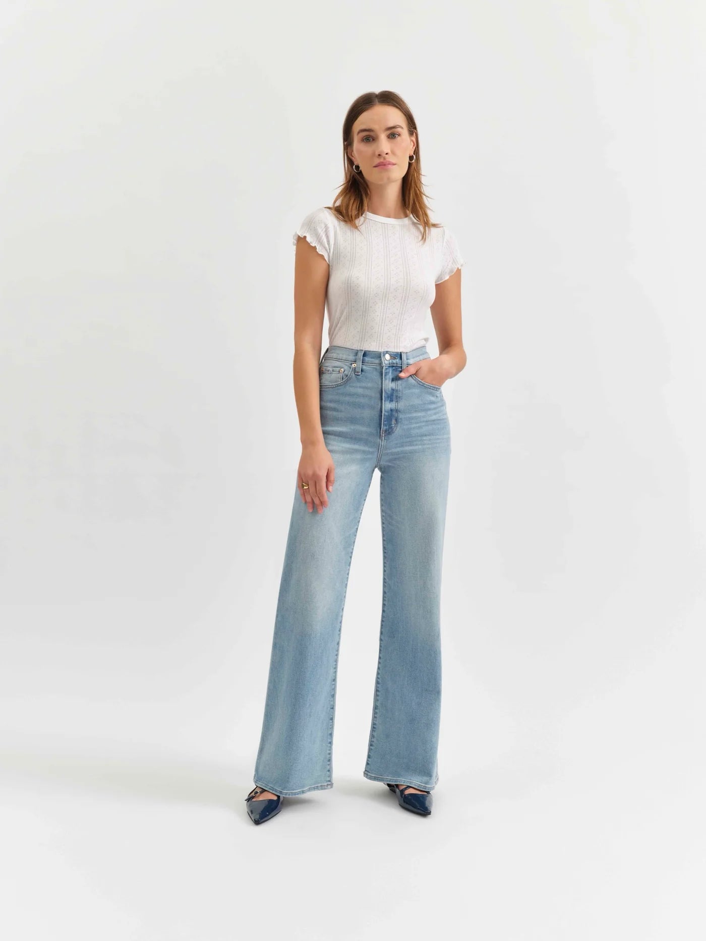 Model wearing the Daze Far Out High Rise Wide Leg Jeans in Blooming Vintage. These light-wash, high-rise jeans feature a dramatic wide-leg silhouette and a flattering fit, made with Comfort Stretch denim for ease of movement.