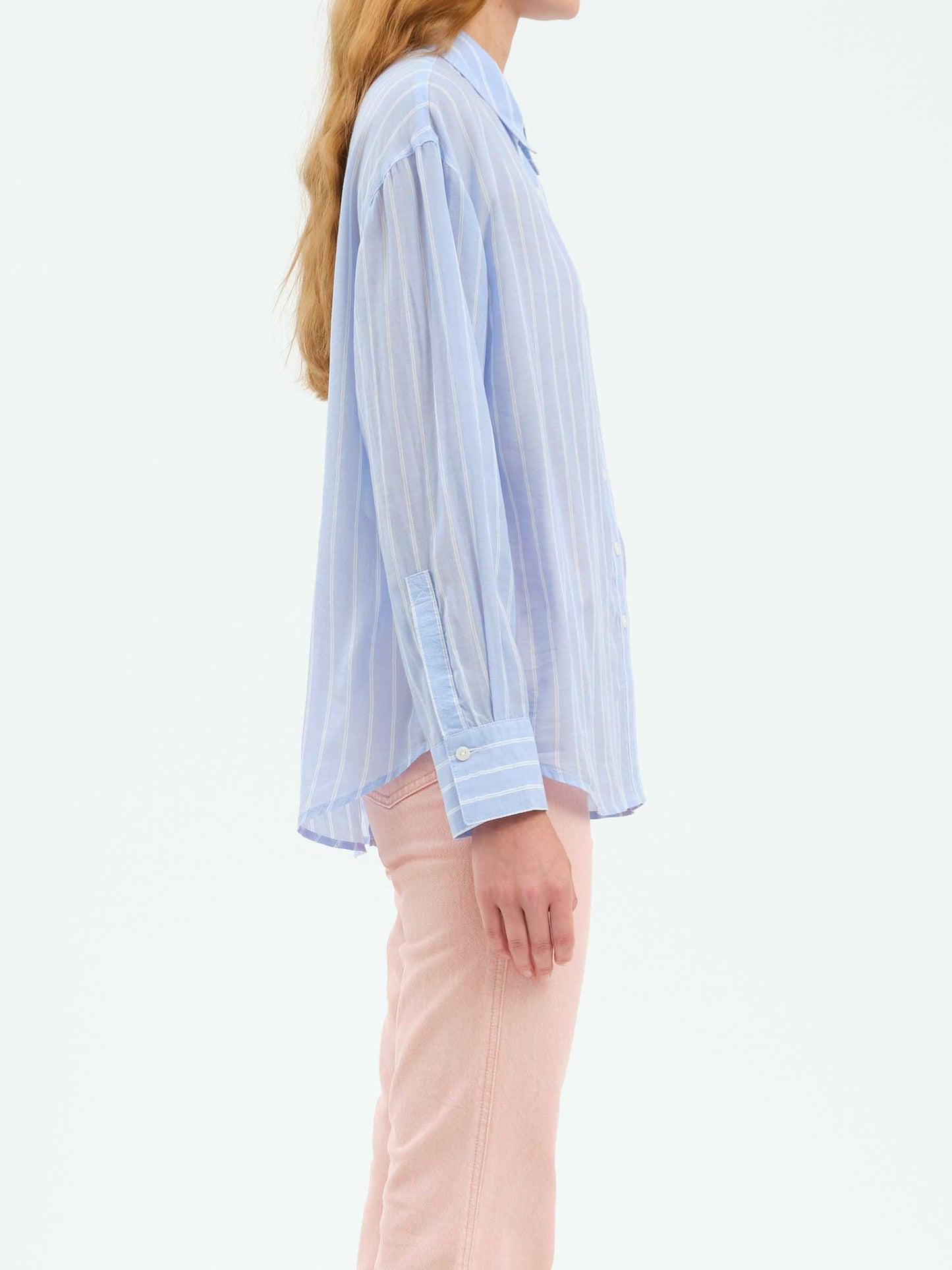 Side profile of the Daze Lotus Back Tie Long Sleeve Shirt, emphasizing the slightly oversized fit and long sleeves with buttoned cuffs.