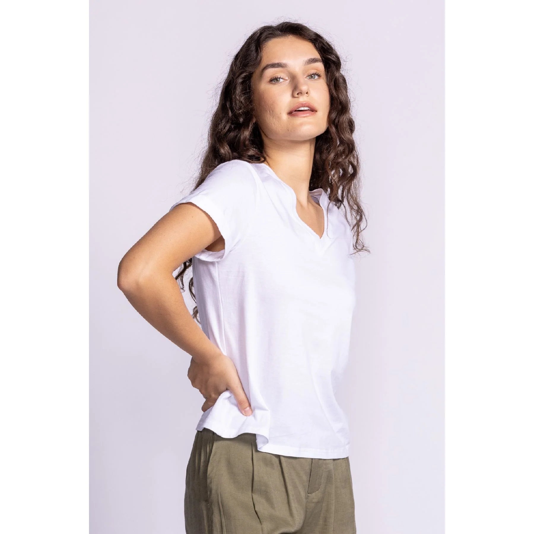 Side view of Pink Martini's Dayna Top. A white V-neck T-shirt, highlighting the lightweight material, rolled sleeves, and effortless drape.