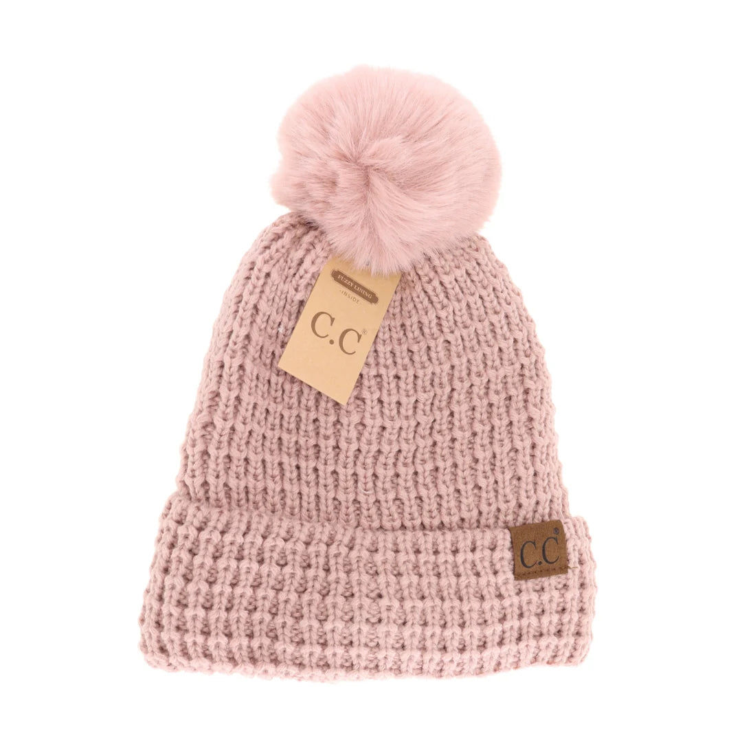 C.C Beanie Knit Pom-Pom Hat in dusty pink, displayed on a clean white background, featuring a soft faux fur pom-pom and leather logo tag.