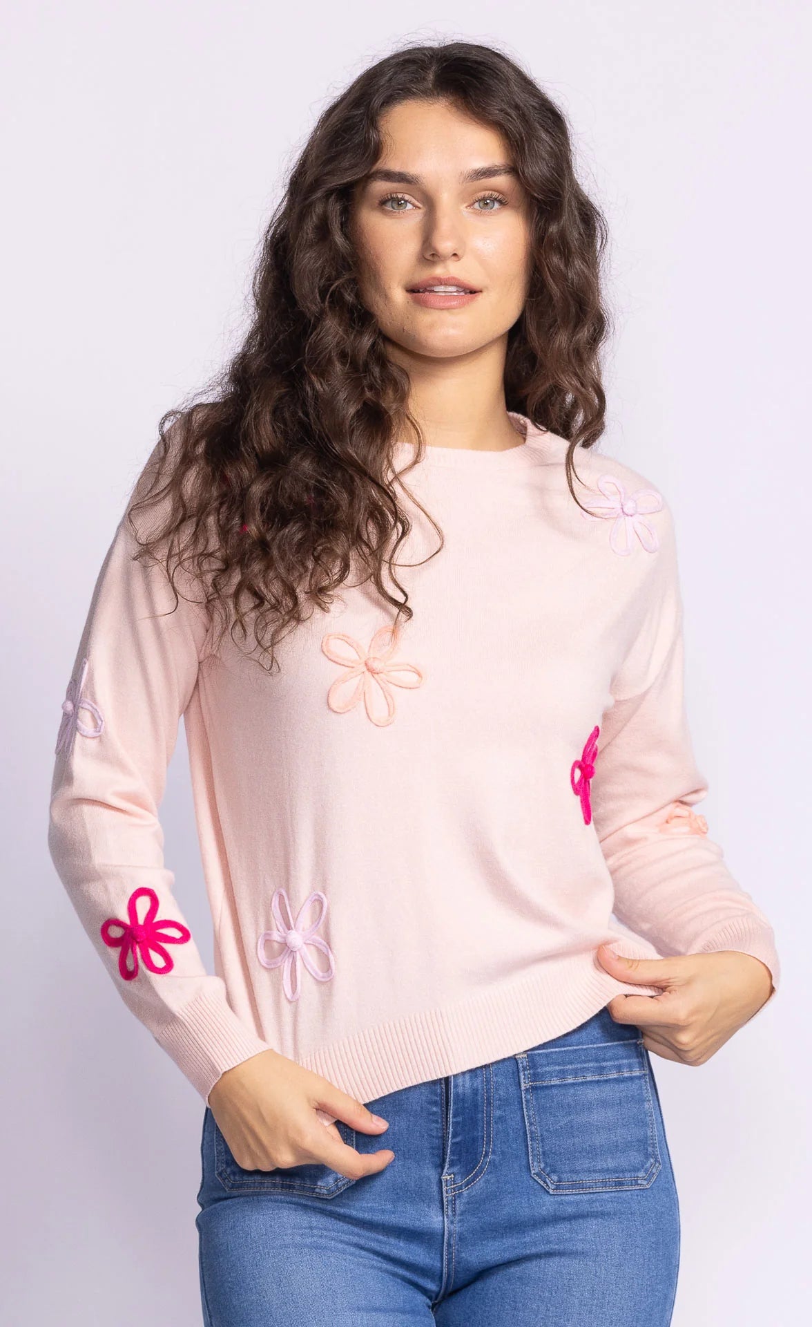 Full front view of the Pink Martini Evie Sweater in light pink, showcasing its cozy knit fabric, round neckline, and bold floral embellishments.