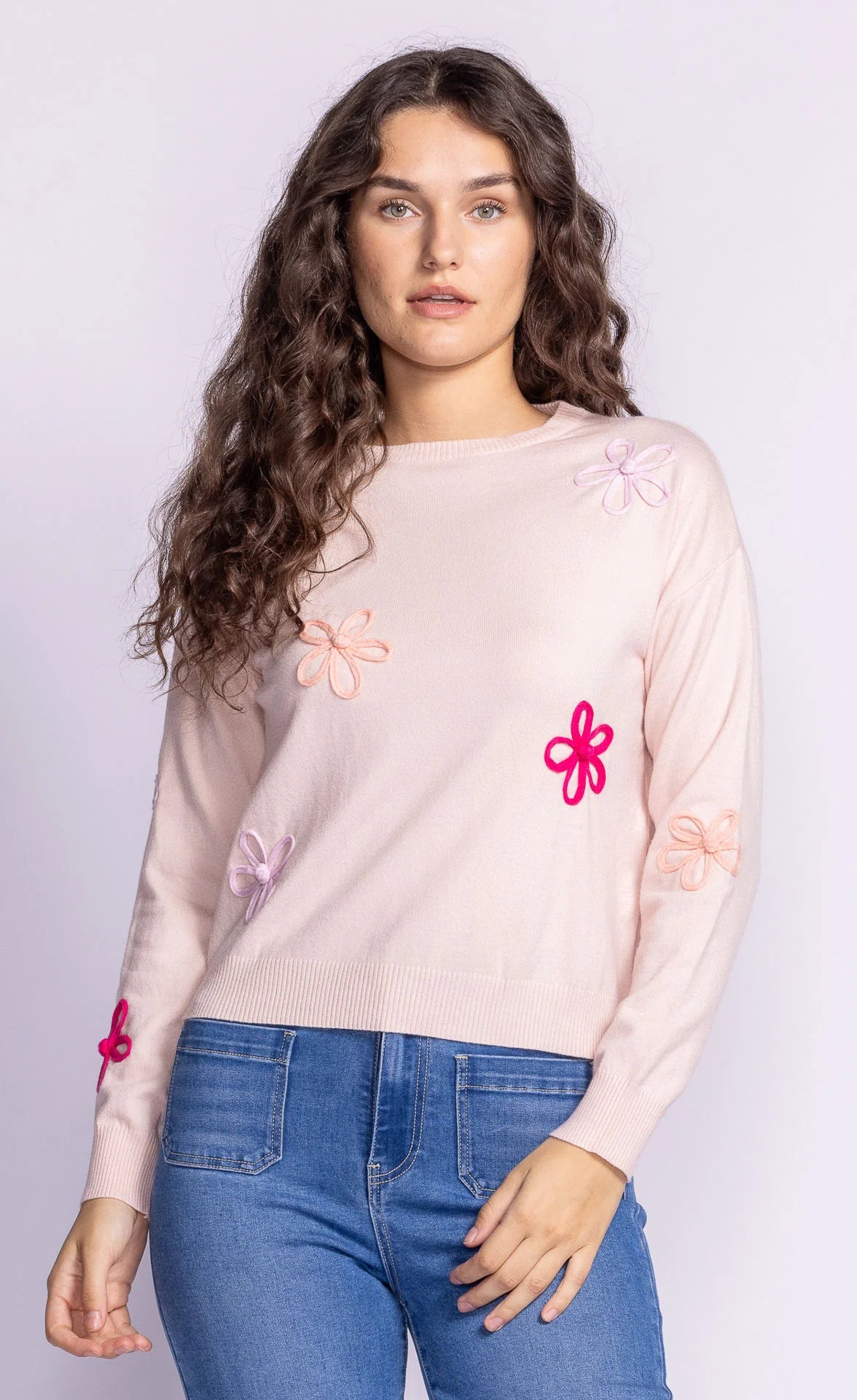 Side angle view of the Pink Martini Evie Sweater, displaying its long sleeves with vibrant floral appliqués on a soft knit fabric.