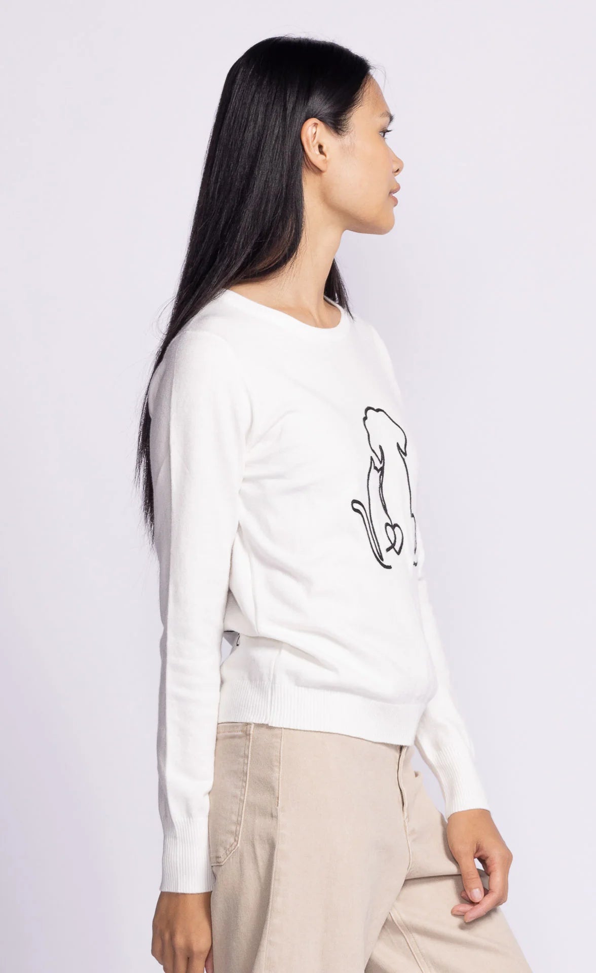 Model showcasing the side of the Friends Forever Sweater by Pink Martini, highlighting the animal print embroidery seen on the front.