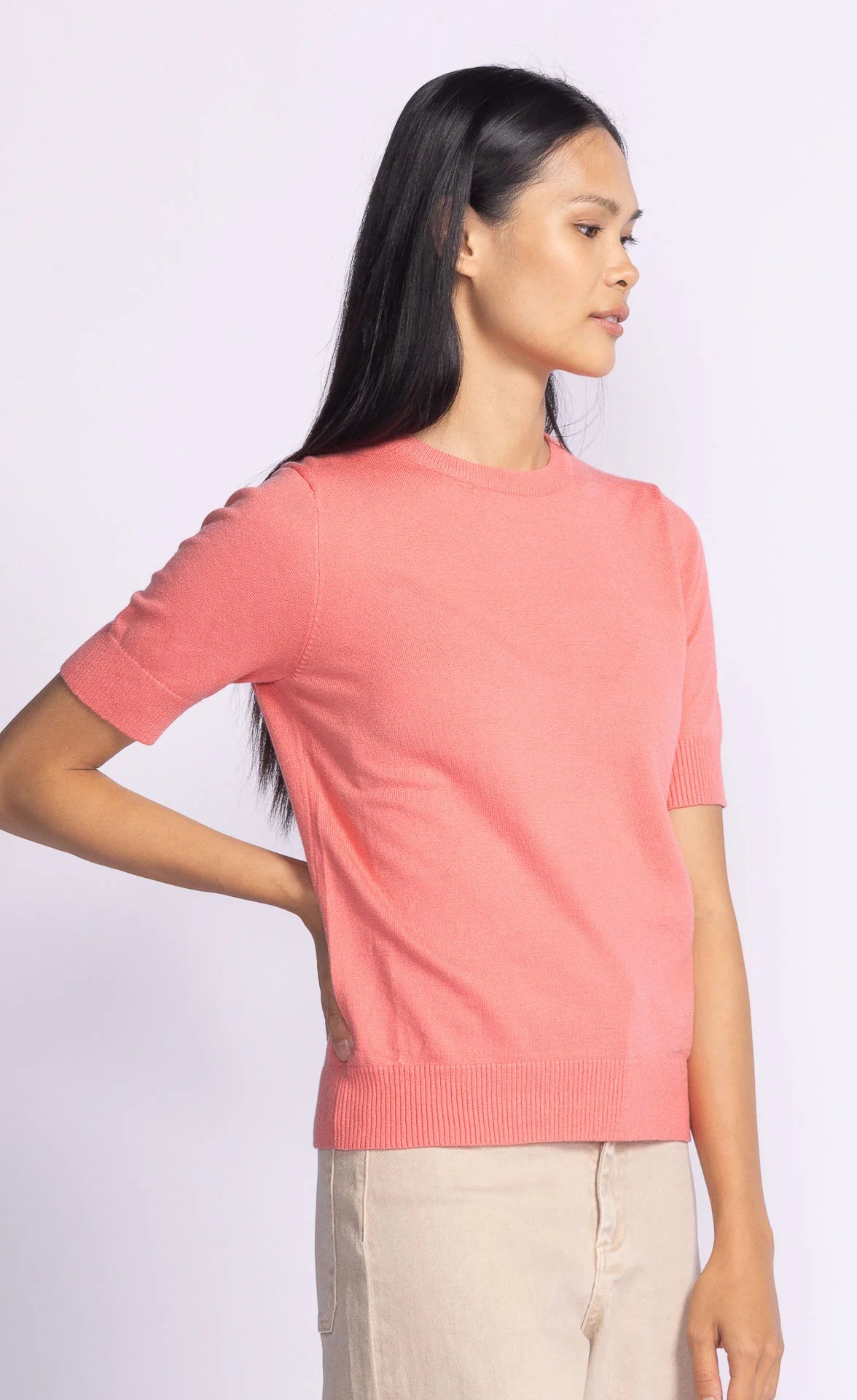 Angled front view of the Pink Martini Sandy Top in coral, showcasing its relaxed fit and breathable knit fabric.