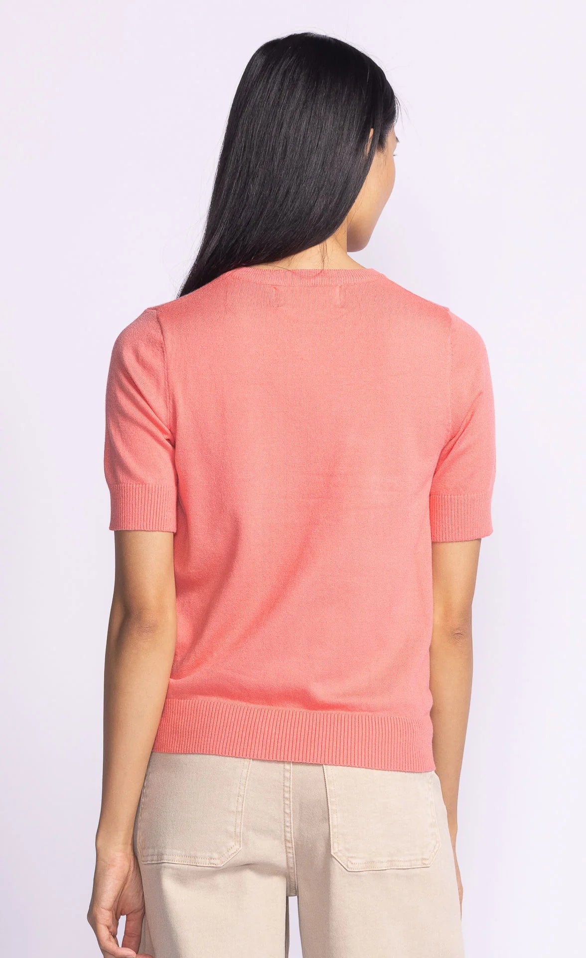 Back view of the Pink Martini Sandy Top in coral, featuring a clean, minimalistic design with a ribbed hem and lightweight fabric.