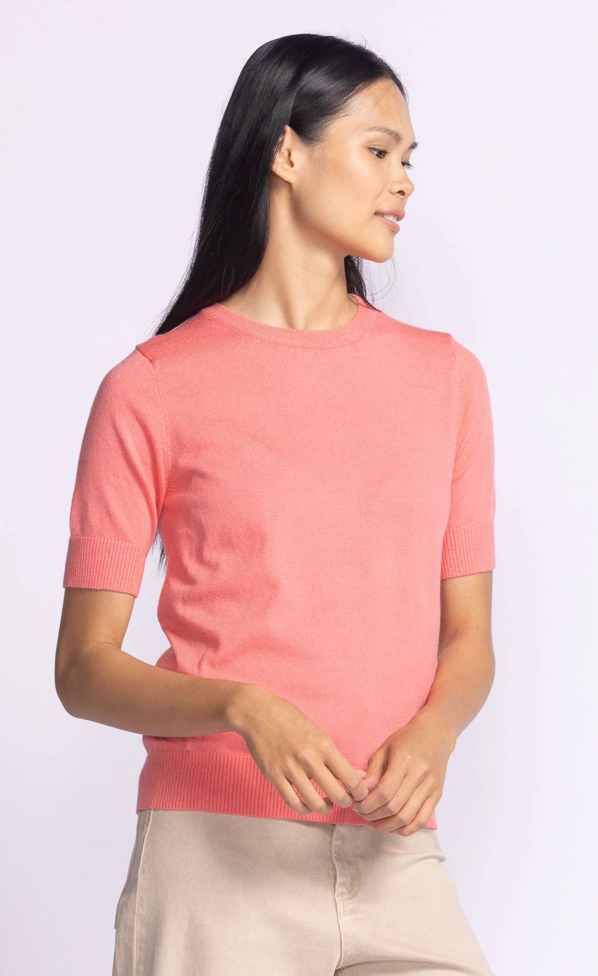 Side profile of the Pink Martini Sandy Top in coral, highlighting its soft knit material and ribbed sleeve detail.