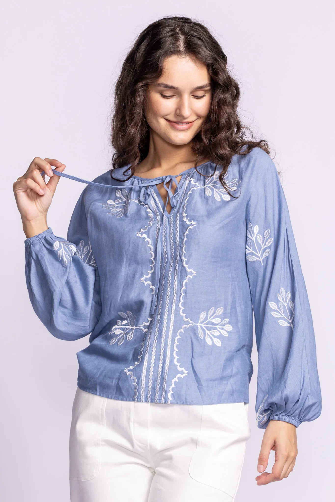 Front view of the Soya Concept Whitney Top in blue, a breezy linen-viscose blouse with white embroidery, a tie neckline, and long billowy sleeves.