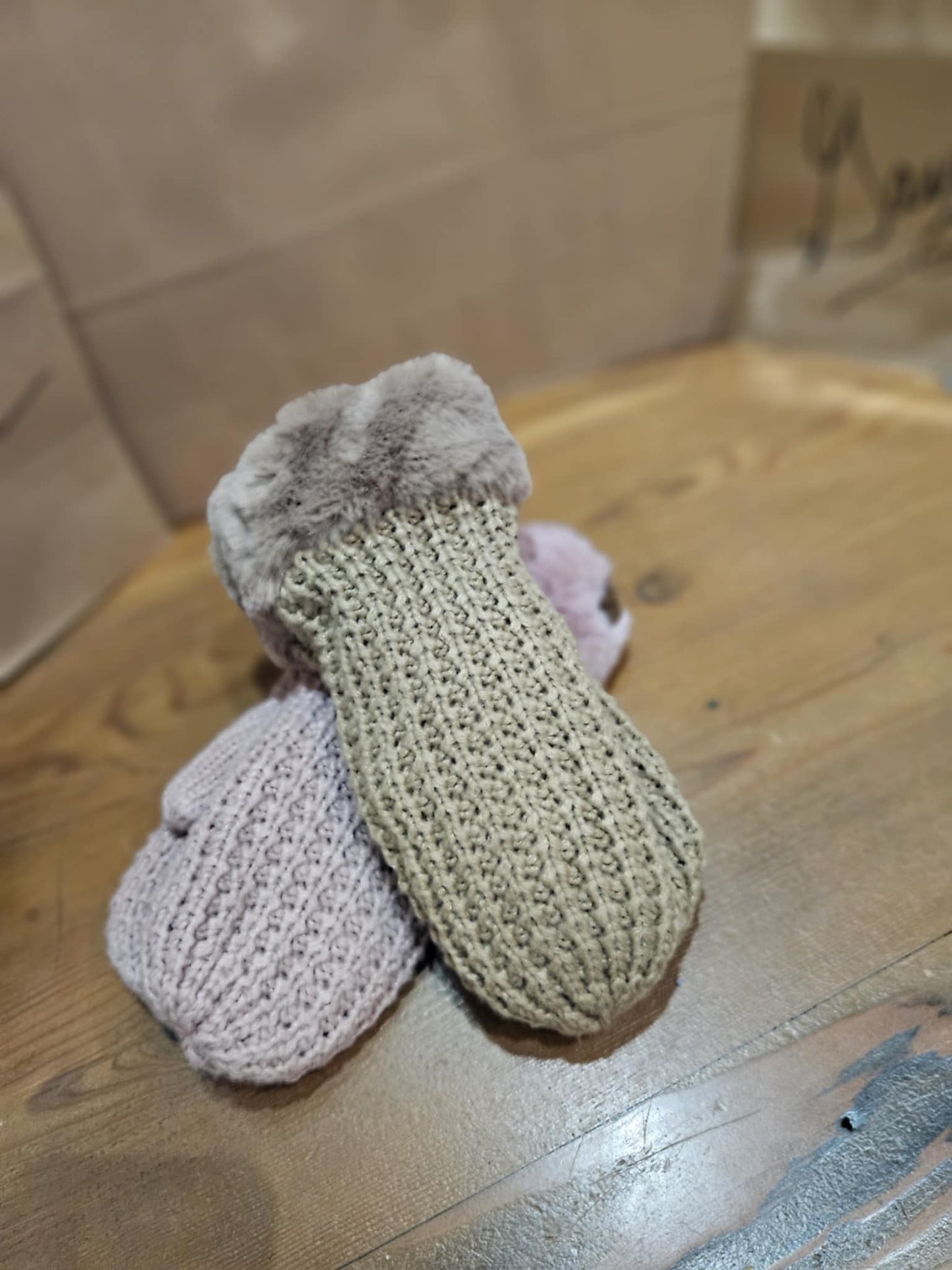 Flat lay of C.C Waffle Knit Mittens in dusty pink and tan, showcasing the fluffy faux fur cuffs and cozy waffle knit design on a wooden surface.